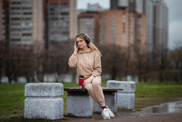 young woman listening to music with headphones on a cloudy day - 495524796