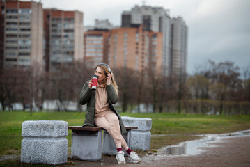 young woman listening to music with headphones on a cloudy day - 495524797