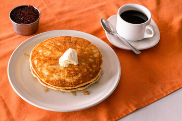 Hot cakes con contenedor de mermelada de fresa y taza de café 