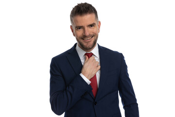 businessman with a wide smile is arranging his tie