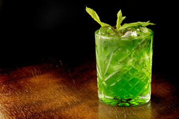 refreshing mint green cocktail with ice cubes front view on wooden table