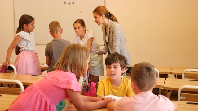 Interested preteen pupils divided into small groups, discussing learning material in classroom. Group work as effective teaching method