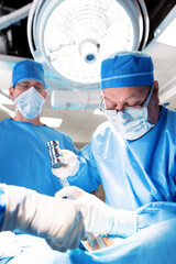 Specialist doctors operating on patient under surgical light