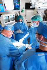 Medical team wearing scrubs operating on anaesthetized patient - obrazy, fototapety, plakaty