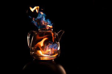 Fire within a see through glass tea pot showing beautiful orange and blue flames inferno giving the idea of substance or alcohol abuse.