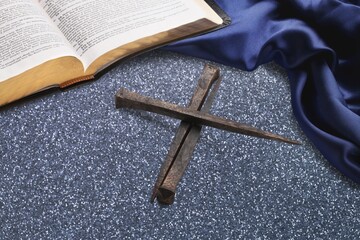 Wooden christian cross on wooden desk background.