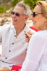 Happy retired Caucasian couple holding hands on beach