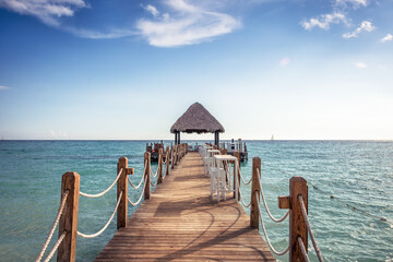 Beach pier leading into the sea with clear blue sky and turquoise water as vacation lifestyle scenery