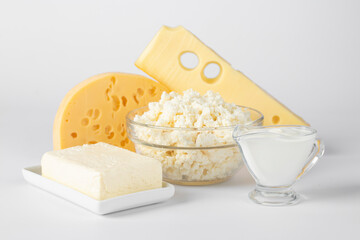 Hard cheese, cottage cheese, butter and sour cream on a white background