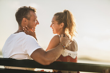 Couple Sitting On Bench And Enjoying Time On A Vacation Near The Beach