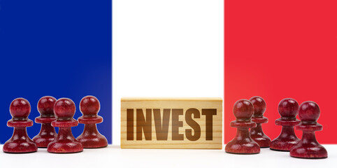 Against the background of the flag of France, pawns and a sign with the inscription - invest