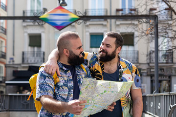 Young gay couple with tourist map at the exit of a transport station. Concept of people traveling...