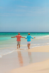 Retired couple paddling in ocean holding hands Bahamas