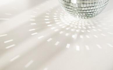 Disco ball on a white background with shadows and casts rays of bright light. Glare and light reflection effect. Copy space.