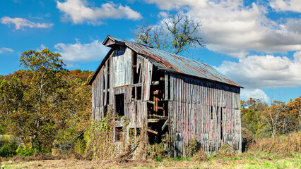 Rural countryside farm landscape with aging dilapidated barn under a cloudy sky