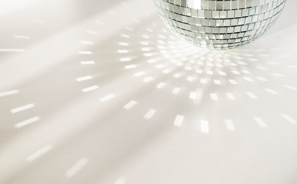 Disco Ball On A White Background With Shadows And Casts Rays Of Bright Light. Glare And Light Reflection Effect. Copy Space.