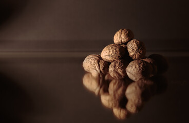 The walnuts heap close-up. Copy space. Beautiful dark background with healthy food. Ingredient. Useful brain nutrients. Nut is a tasty diet snack. Macro. Brown color. Wallpaper. Photo art still life