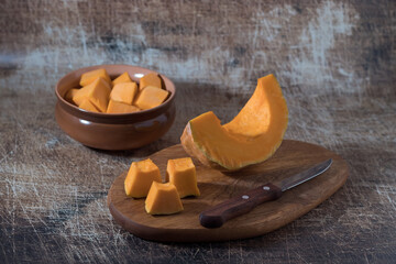 raw pumpkin prepared for cooking and pumpkin seeds on a wooden table.