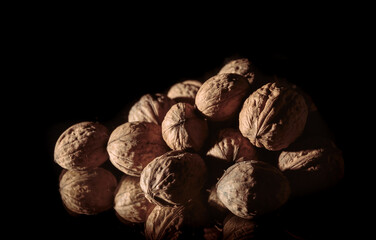 Fototapeta na wymiar A walnuts heap close-up. Copy space. Beautiful still life on a dark background. Healthy food. Ingredient. Useful brain nutrients. Nut is a tasty diet snack. Brown color. Wallpaper. Photo art. Banner