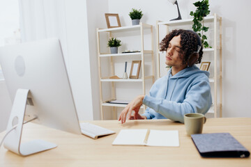 A young man sitting at a table in front of a computer music technologies