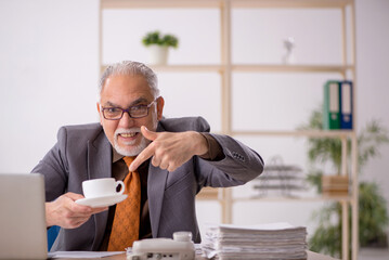 Old male employee drinking coffee during break