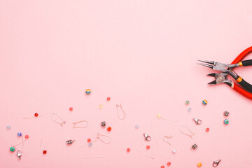 Jewellery making concept with beads and tools over pink paper background