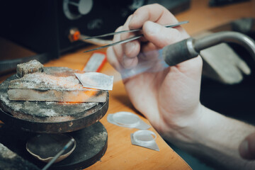 Heating. Close up hands of jeweller, goldsmiths making of silver ring using burner professional tools. Workshop, artwork.