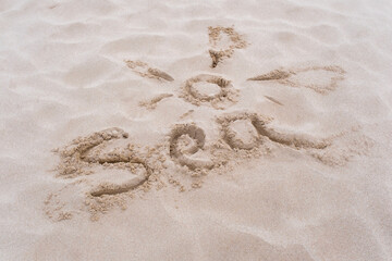 Sun picture and inscription sea or beach, shore. Drawing on sand surface texture. Top view, copy space. Vacation and relax concept.