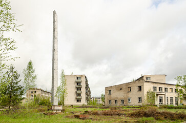 Fototapeta na wymiar Abandoned white brick multistorey houses and monument. Forgotten, abandoned ghost town Skrunda, Latvia. Former Soviet army radar station.
