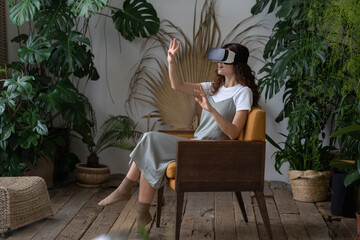 Excited young woman interior designer or florist enjoy vr gaming using virtual reality interface...