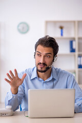 Young male call center operator working at his desk