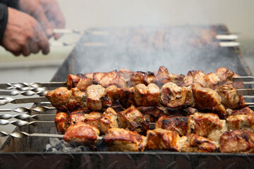 Grilled meat, hands in the background.