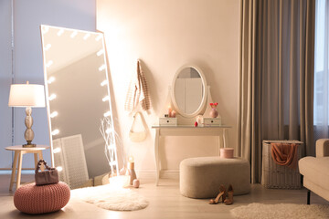 Large mirror with light bulbs and dressing table in stylish room. Interior design