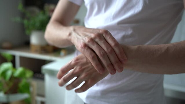 Closeup of man arms massaging painful wrist after work on laptop computer at home, suffering from weakness and tingling, carpal tunnel syndrome, arthritis, neurological disease. Numbness of hand