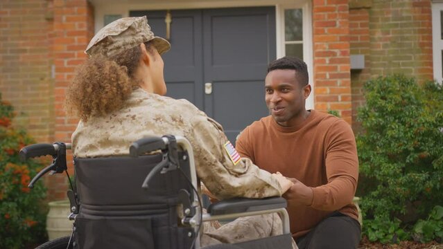 Injured female American soldier wearing uniform sitting in wheelchair talking with husband outdoors - shot in slow motion