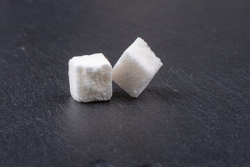 Cubes of white beet sugar refined on a stone background.