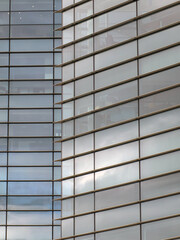full frame modern office architecture abstract with geometric shapes of tall buildings reflecting the blue cloudy sky in large glass windows