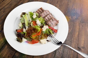Roast rib steak, fried beef meat on a plate with salad.