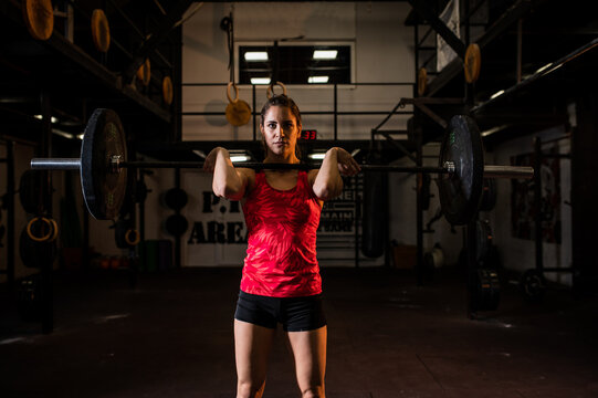 An attractive muscular woman lifts rubber weight plate in a gym