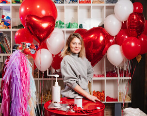 woman with composition of white, red, foil balloons in form of heart and ball. 