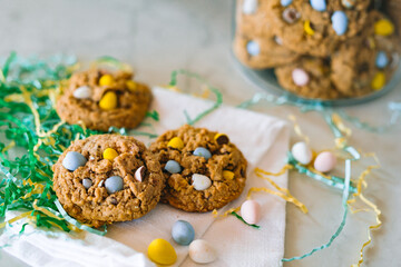 Fototapeta na wymiar Oatmeal cookies with chocolate eggs surrounded by Easter grass
