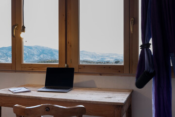 Mesa rústica con ordenador y libreta, preciosas vistas en la ventana, columpio de yoga acrobático...