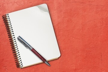 Notepad for writing text with pen on a red background.