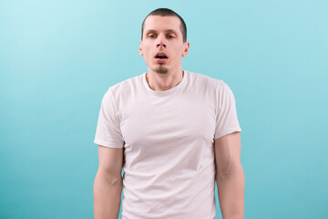 An unmotivated exhausted young man in a white t-shirt with open mouth on a blue background. Arm. Mid Adult. Boring. Bad. Boredom. Boy. Disturb. Lazy. Work. Goatee. Stare. Stress. Upset. Woke up