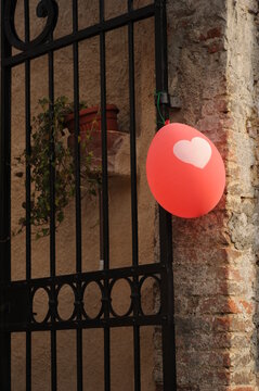 Cancello festivo con palloncino rosso dalla stampa a cuore su sfondo di muro con pianta.