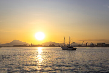 Sol nascendo com um barco de pesca ancorado