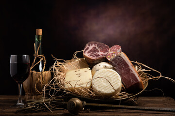 Assorted homemade cheese, salumi on wooden table with a wooden background