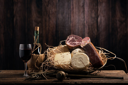 Assorted homemade cheese, salumi on wooden table with a wooden background