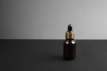 glass brown bottle with pipette with essential oil on a dark grey background with copy space....