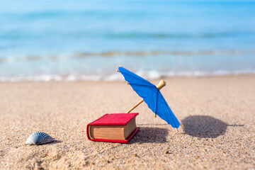 Nostalgic Beach Holiday / Summer beach nostalgia leisure objects in miniature: seashell, parasol and book (copy space) - obrazy, fototapety, plakaty